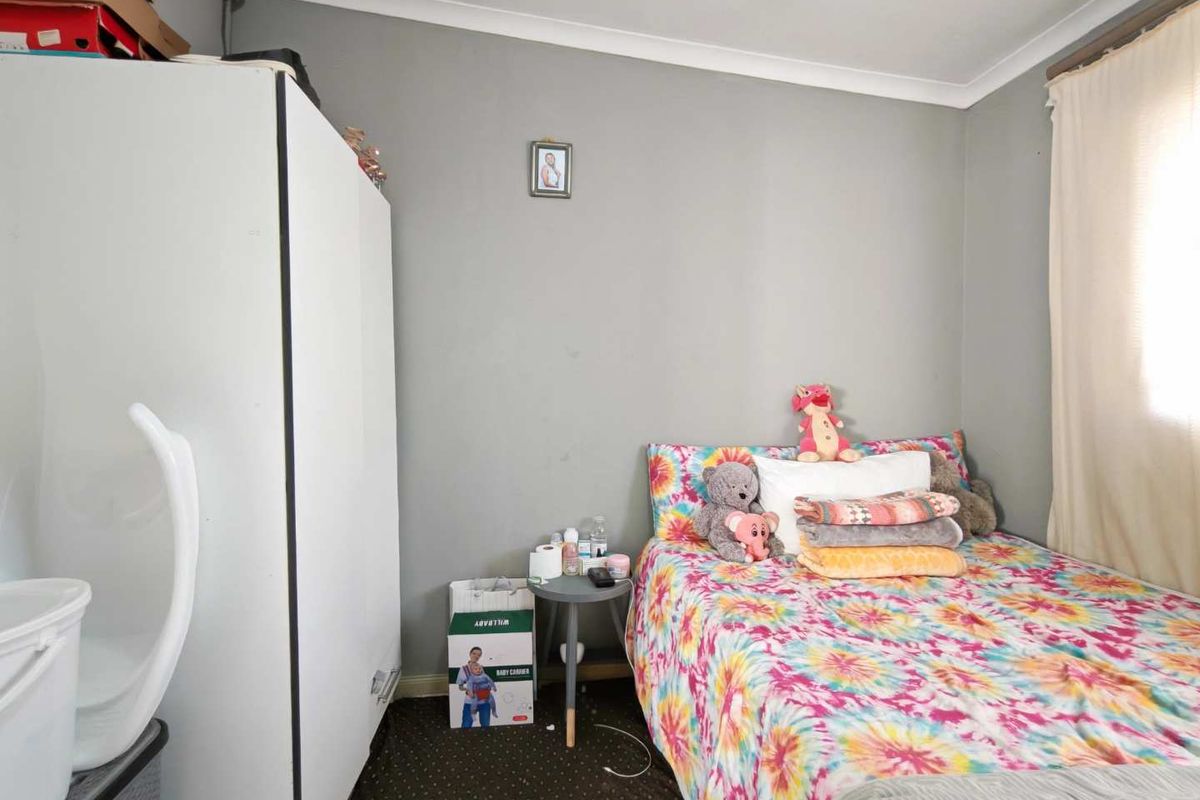 A standard bedroom featuring neutral grey walls, coving, and a window with a curtain rail.