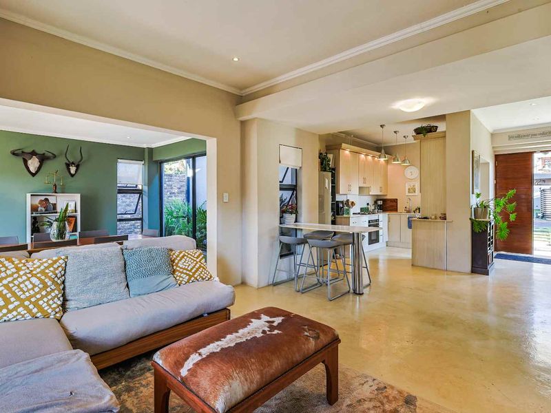 Spacious open-plan living area featuring polished concrete floors, a modern kitchen with breakfast bar, and seamless flow to the outdoor space.