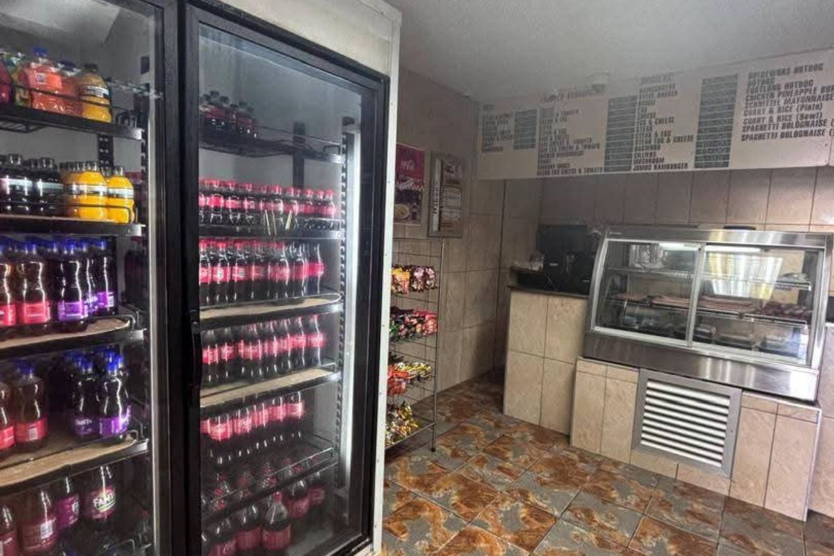 Commercial kitchen area featuring built-in glass display refrigerators, a food service counter, and tiled flooring, suitable for a takeaway or cafe business.