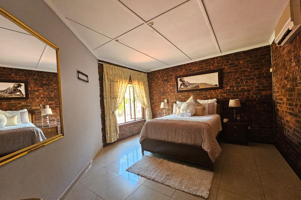 A bedroom featuring exposed brick feature walls, tiled flooring, and a split-system air conditioning unit.