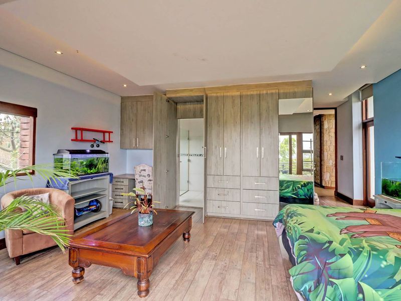Spacious bedroom featuring extensive built-in cabinetry, modern laminate flooring, recessed ceiling lighting, and direct access to an en-suite bathroom.