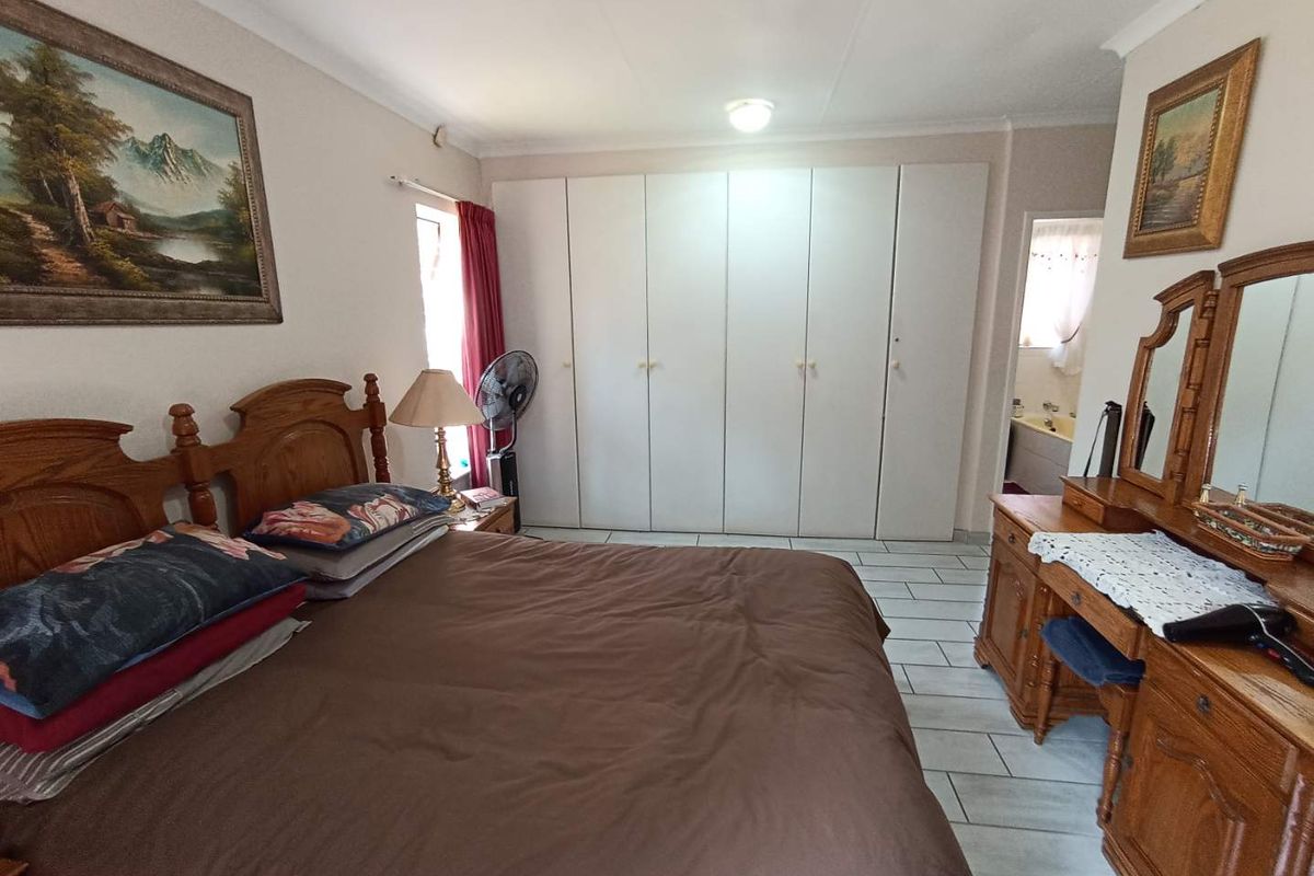 A spacious bedroom featuring built-in cupboards, tiled flooring, and direct access to an adjoining bathroom.
