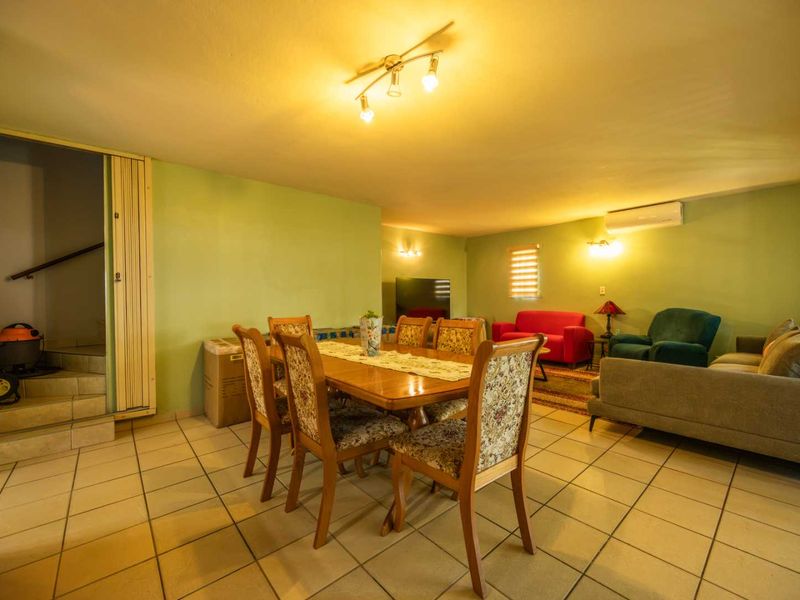 Spacious open-plan living and dining area featuring tiled flooring, split-system air conditioning, and direct access to an internal staircase.