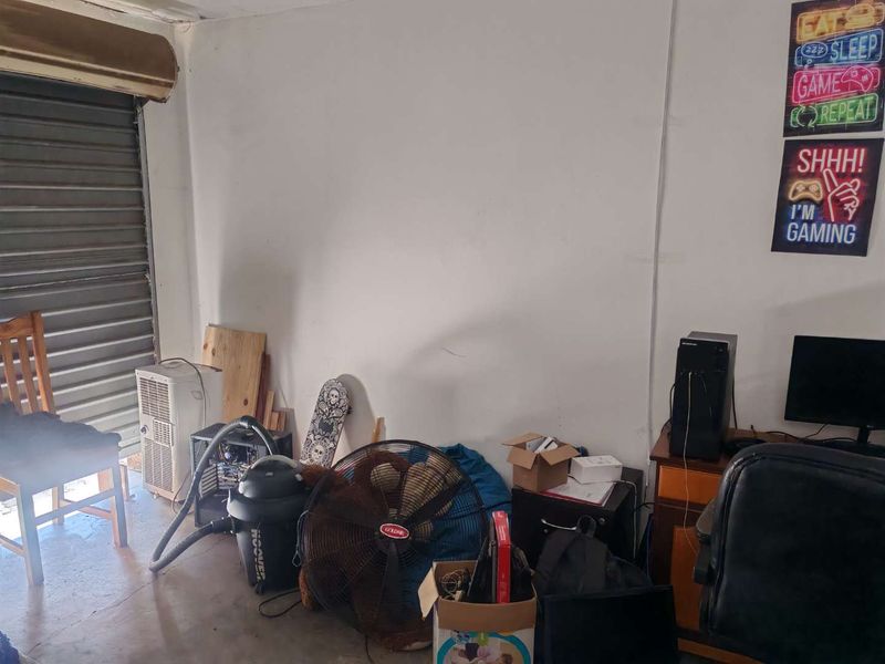 A functional garage space featuring a roller shutter door and concrete flooring, currently utilized as a multi-purpose storage and workspace area.