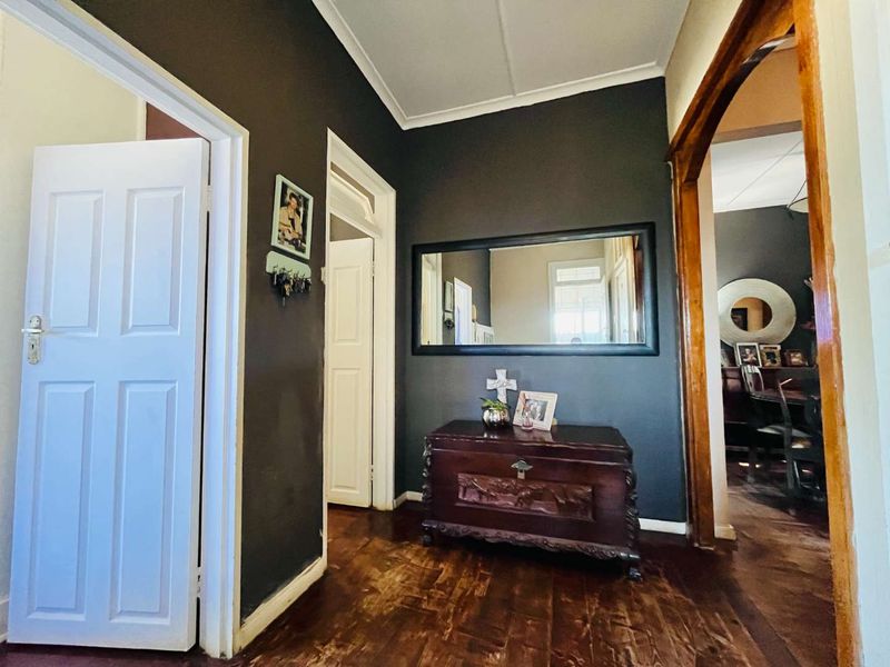 A welcoming entrance hall featuring dark painted walls, polished timber flooring, and a classic arched doorway leading into the adjacent living space.