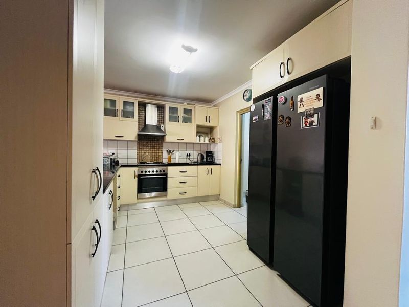 A functional kitchen featuring built-in cabinetry, a stainless steel oven with extractor fan, tiled flooring, and a tiled backsplash.