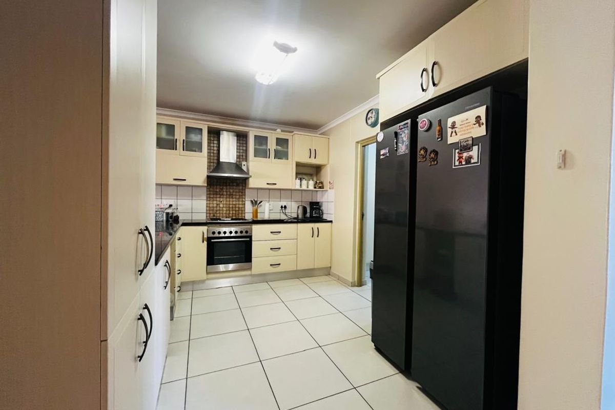 A functional kitchen featuring built-in cabinetry, a stainless steel oven with extractor fan, tiled flooring, and a tiled backsplash.