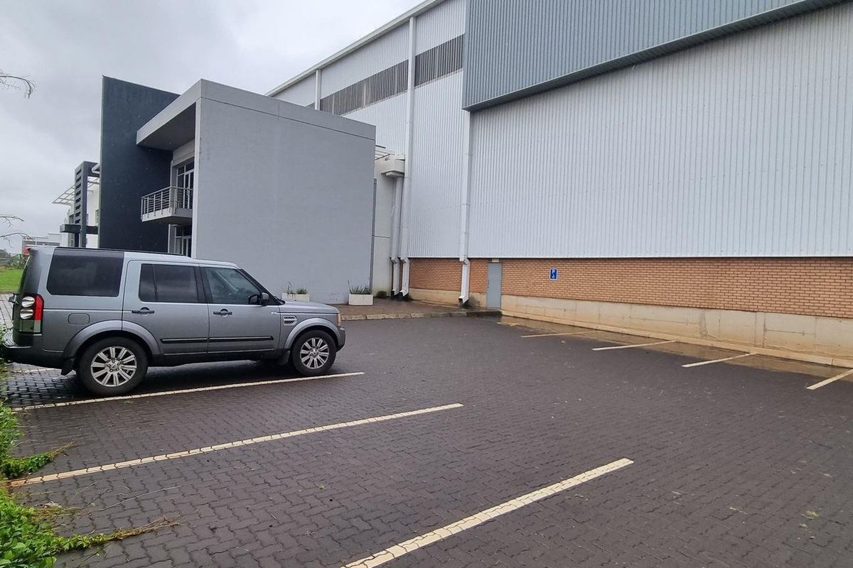 Exterior view of an industrial property featuring a paved parking area, brick and metal cladding facade, and modern architectural entrance detail.