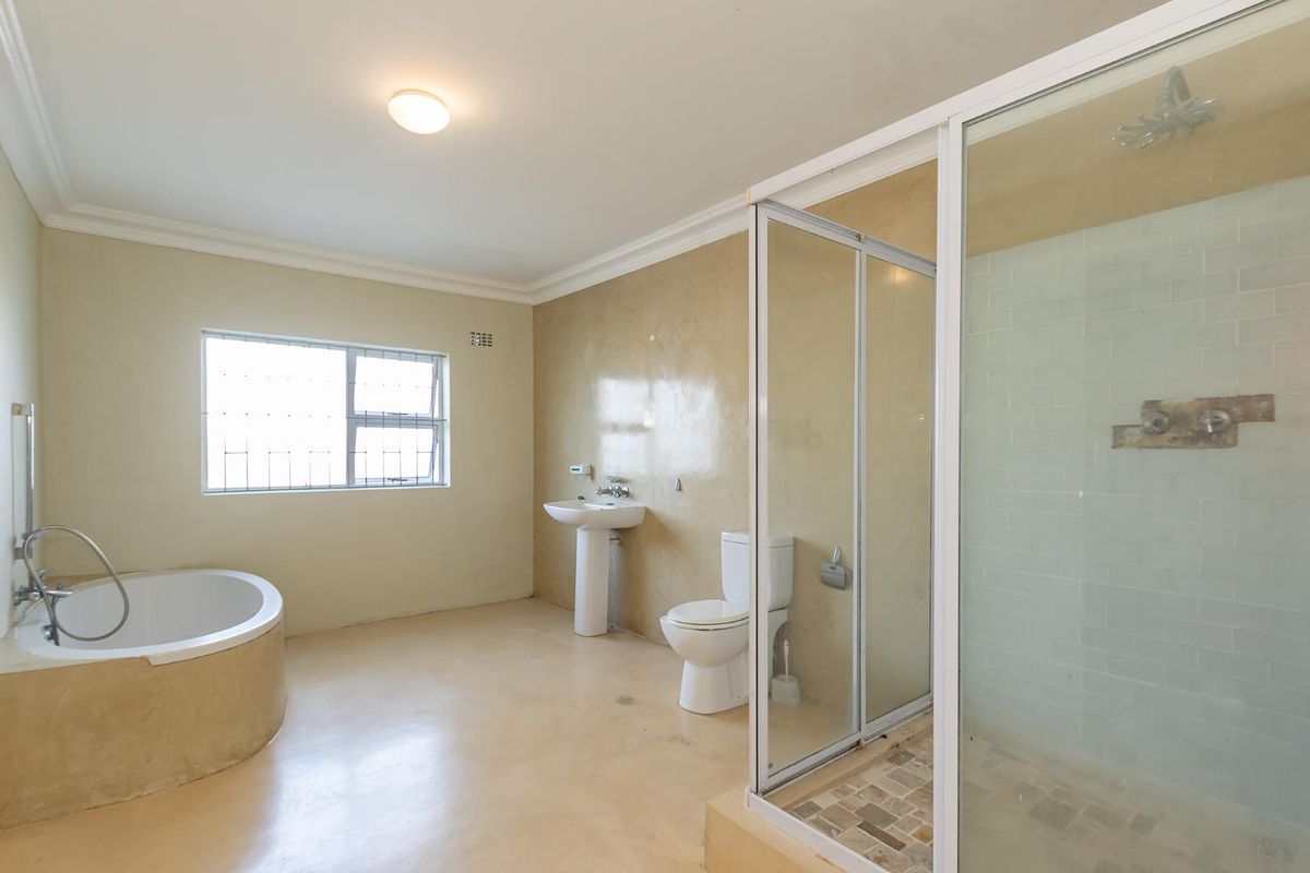 Spacious bathroom featuring a built-in bathtub, pedestal basin, toilet, and a separate glass-enclosed shower with tiled flooring.