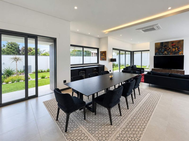 Spacious open-plan living and dining area featuring modern tiled floors, recessed lighting, ducted air conditioning, and large sliding doors opening to the garden.