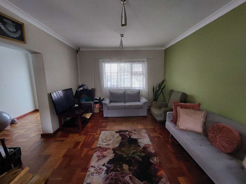A living room featuring classic parquet flooring, cove cornicing, and natural light through venetian blinds, offering a solid foundation for modern interior updates.