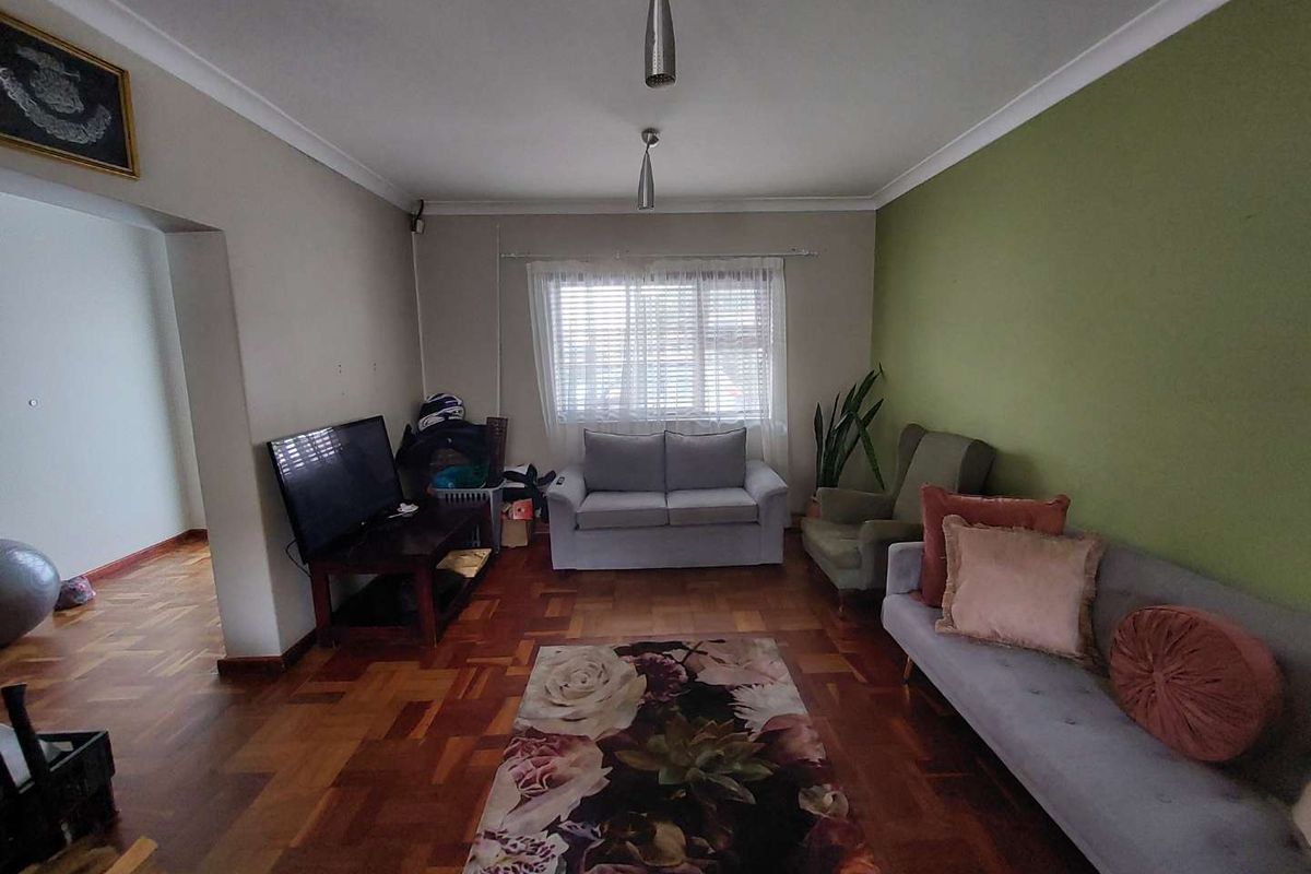 A living room featuring classic parquet flooring, cove cornicing, and natural light through venetian blinds, offering a solid foundation for modern interior updates.