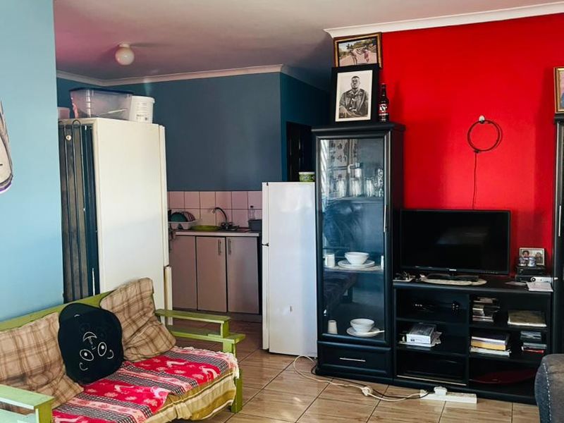 Open plan living area featuring tiled flooring and a compact kitchen corner with built-in cabinetry and sink.