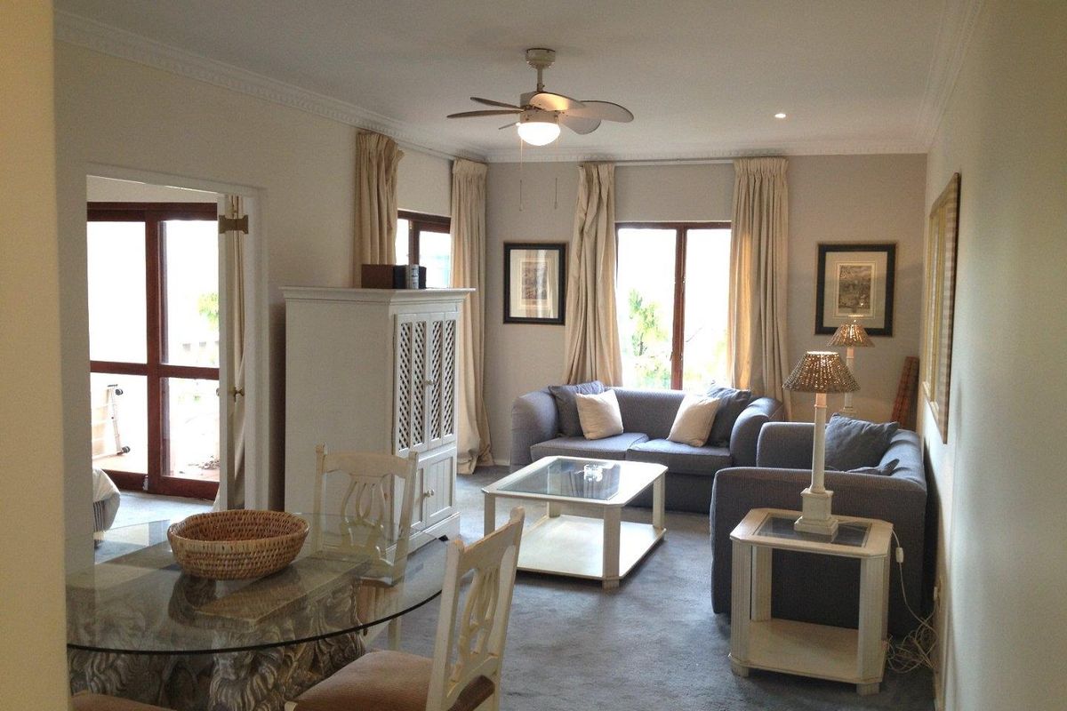 A comfortable living room featuring crown molding, a ceiling fan, and access to an outdoor area through double glass doors.