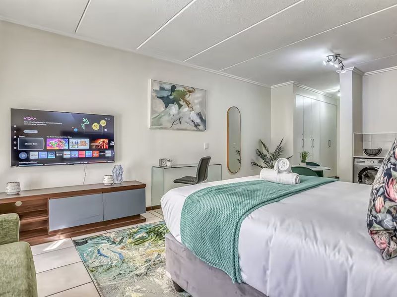An open-plan studio apartment featuring tiled flooring, built-in storage cupboards, and a compact integrated kitchen area.