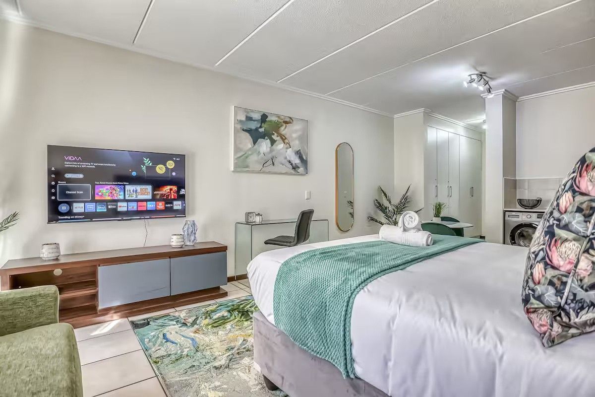 An open-plan studio apartment featuring tiled flooring, built-in storage cupboards, and a compact integrated kitchen area.