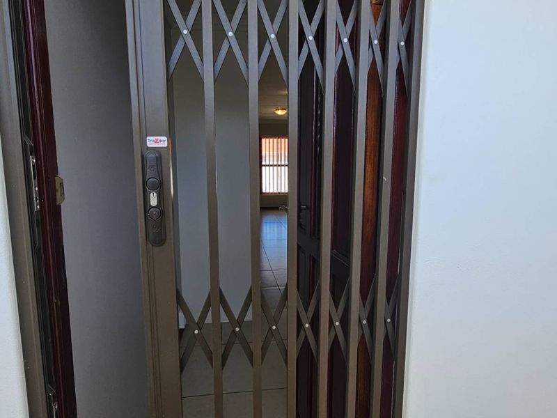 Entrance area featuring a secure metal gate and timber door, providing access to the interior living space with tiled flooring.