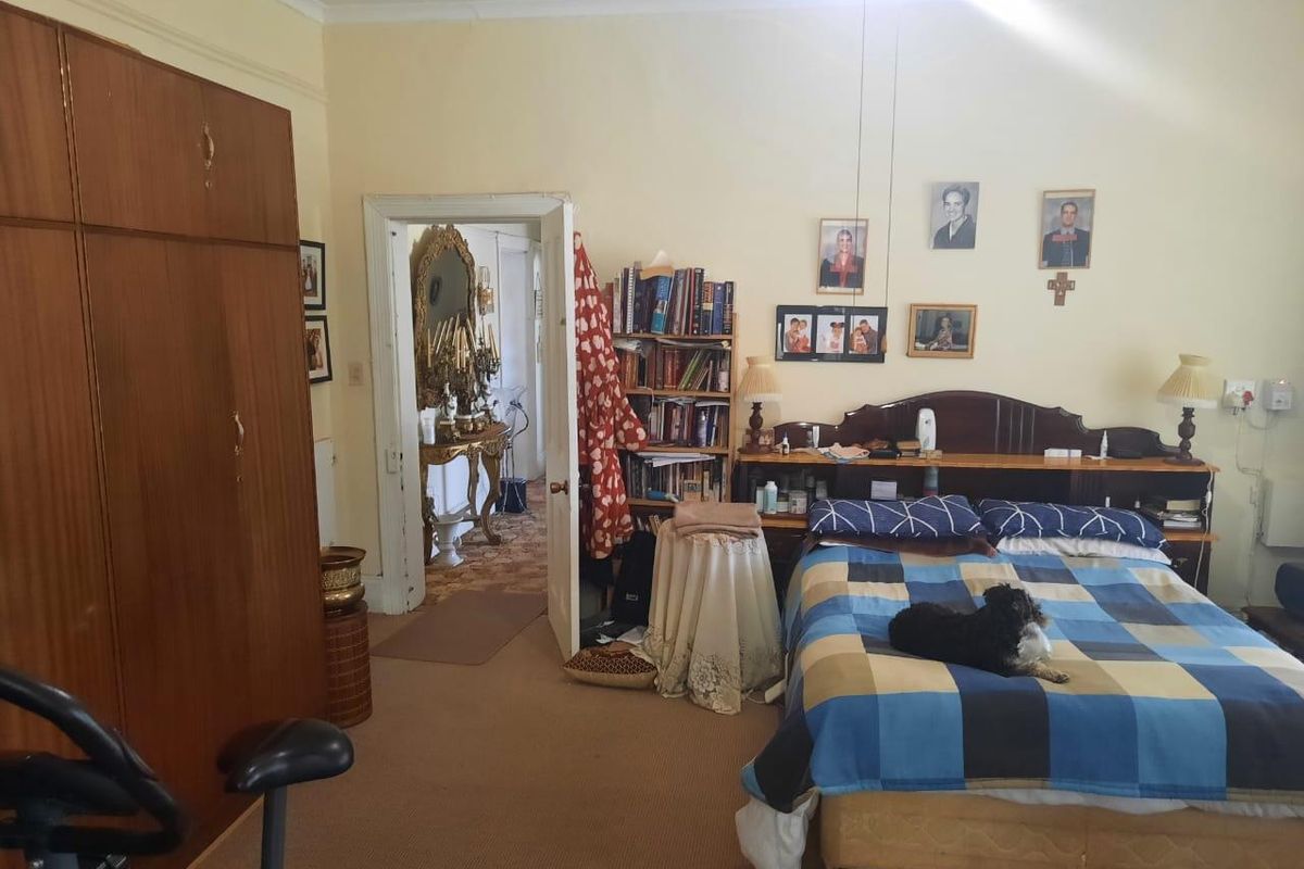 A spacious bedroom featuring built-in wooden cabinetry and carpeted flooring, with an adjoining doorway leading to an adjacent room.