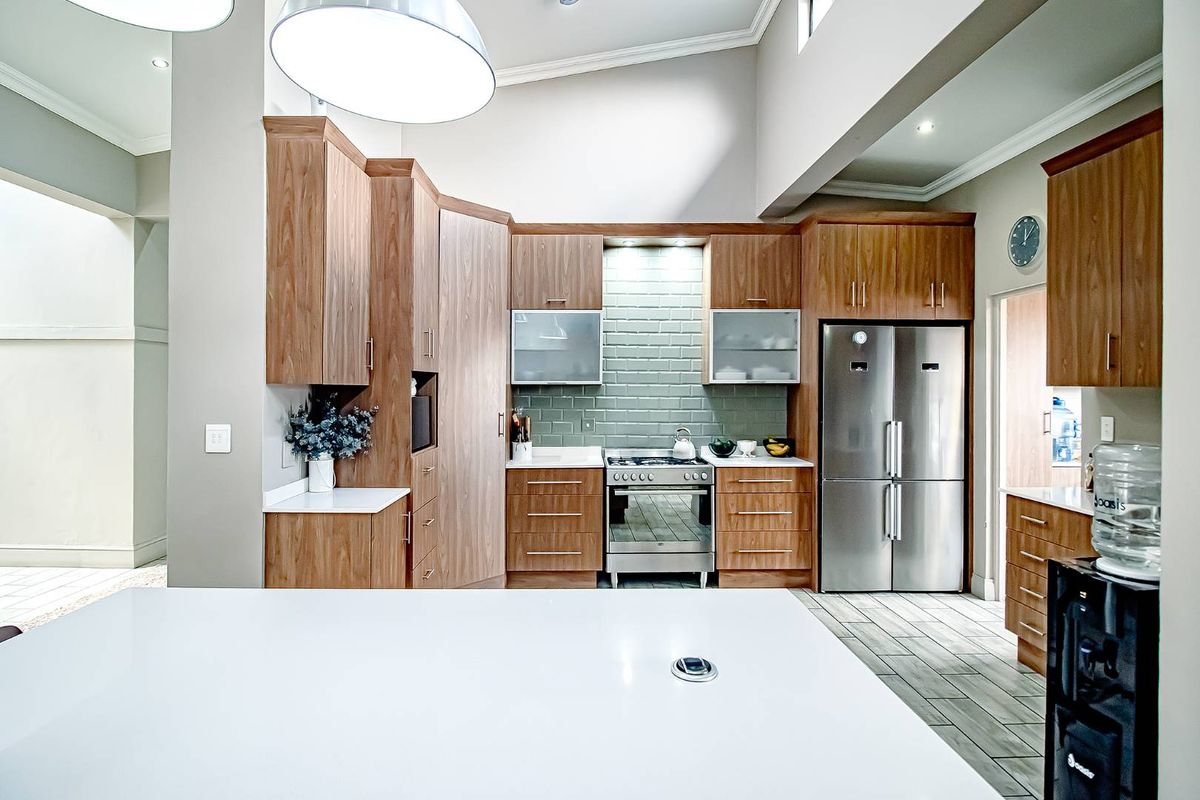 Modern kitchen featuring wood grain cabinetry, subway tile backsplash, stainless steel appliances, and a large central island with stone countertops.