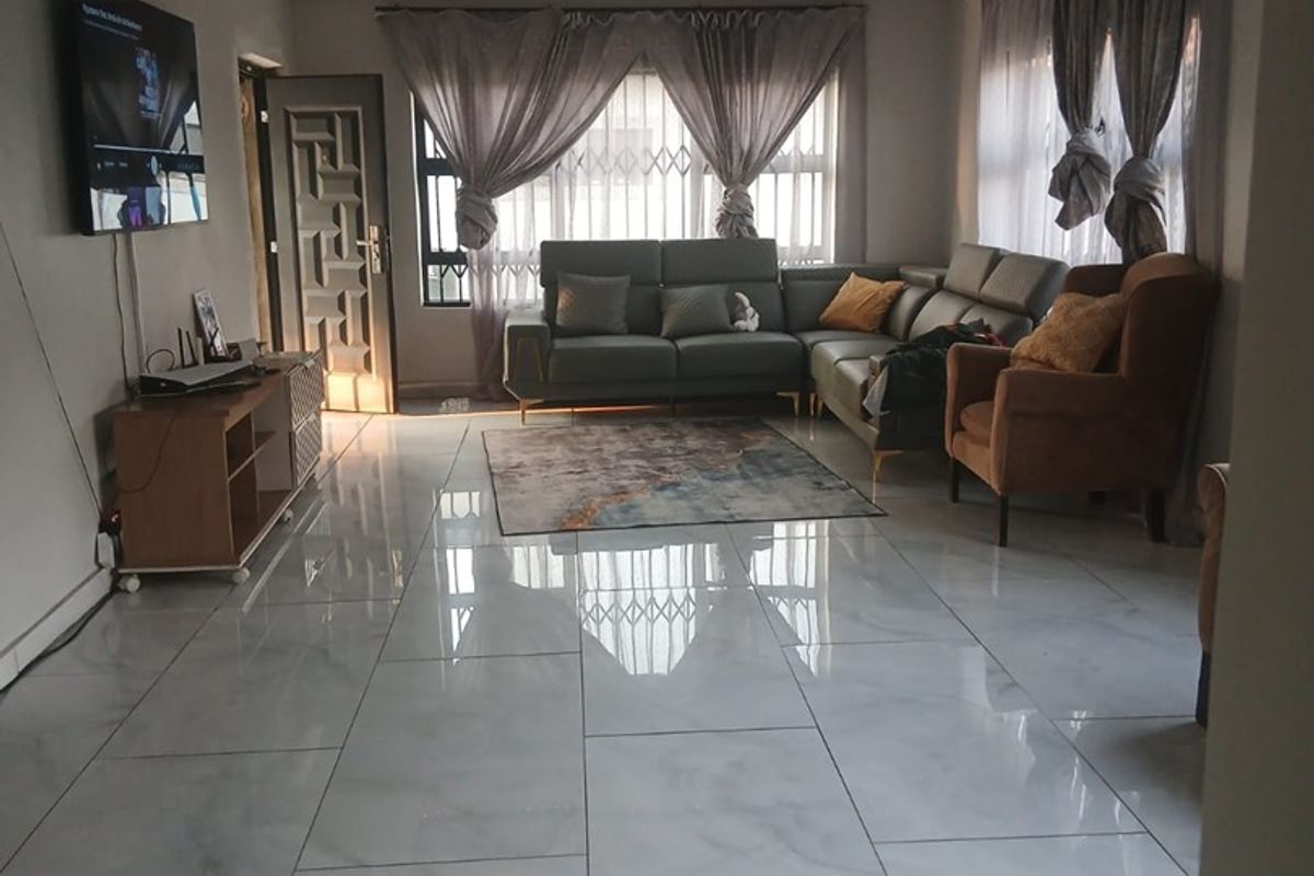 Spacious living room featuring polished porcelain floor tiles, a modern recessed ceiling with integrated cove lighting, and a secure entrance door.