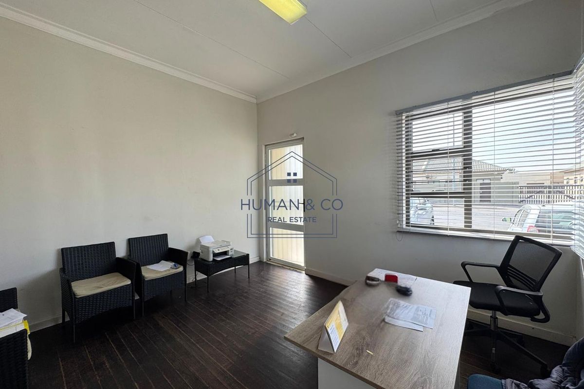 A functional office space featuring laminate flooring, a glass panel door, and venetian blinds, providing a practical work environment with natural light.