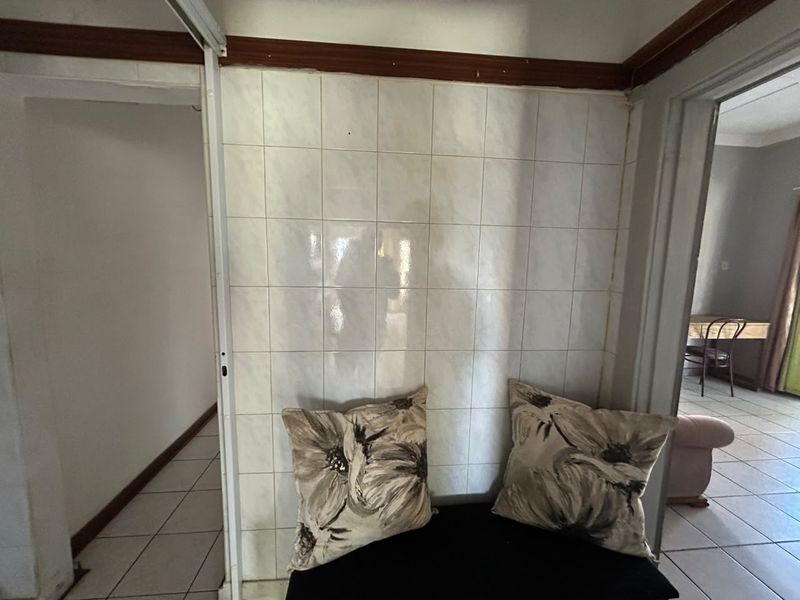 A transitional hallway space featuring tiled wall finishes and tiled flooring, connecting to adjacent living areas.