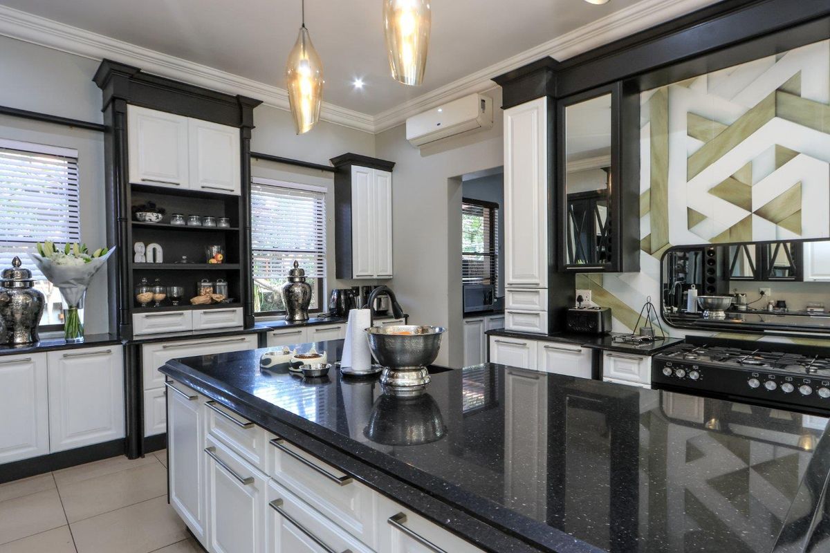 Modern kitchen featuring a large central island with granite countertops, high-end cabinetry, gas range, and integrated appliances in a well-maintained, stylish space.