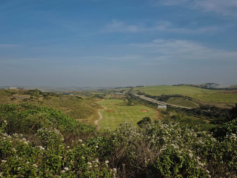 A scenic elevated view overlooking a green golf course fairway set within a rolling natural landscape.