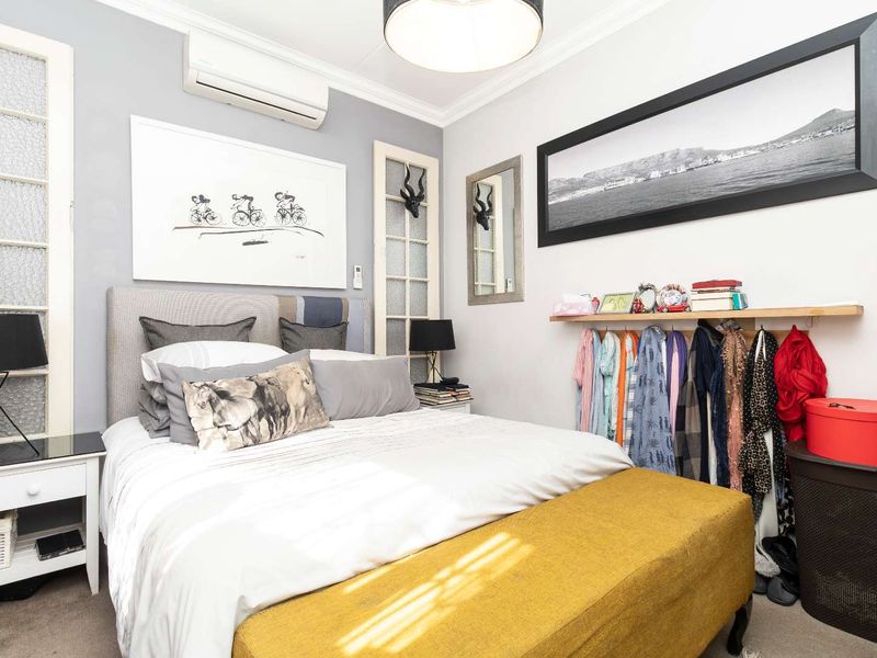 A well-maintained bedroom featuring a wall-mounted air conditioning unit, decorative glass-paneled door detail, and built-in shelving.