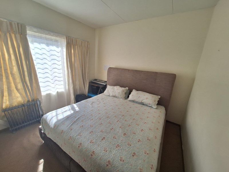 A standard bedroom featuring carpeted flooring and a window with curtain tracks, offering a functional space ready for personal updates.
