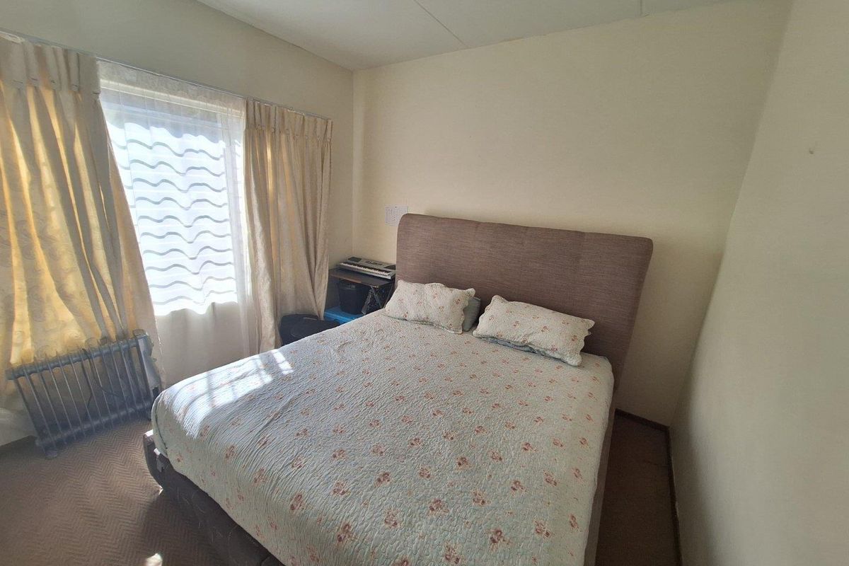 A standard bedroom featuring carpeted flooring and a window with curtain tracks, offering a functional space ready for personal updates.