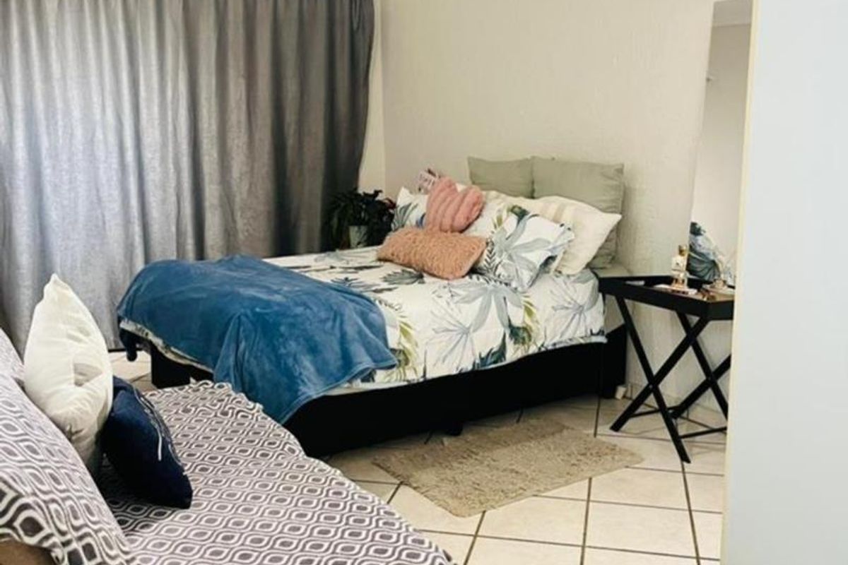 A bedroom featuring tiled flooring and large window curtains, providing a functional and comfortable living space.