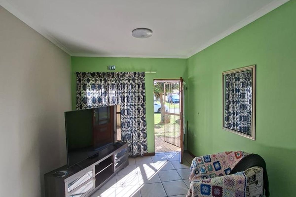 A living room area featuring tiled flooring, a security gate at the entrance, and direct access to the exterior.
