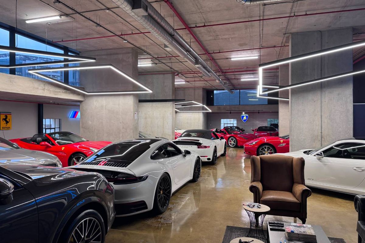 Spacious industrial-style garage featuring exposed concrete ceilings, polished concrete floors, and modern linear lighting, designed for high-end vehicle storage.