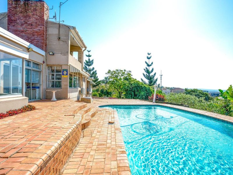 Outdoor pool area featuring a brick-paved patio, swimming pool, and direct access to the home via sliding glass doors with elevated views.