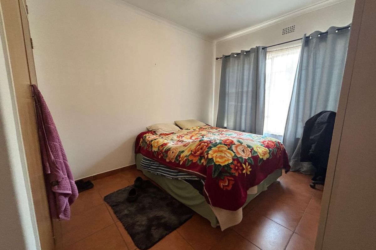 A functional bedroom featuring tiled flooring and a built-in cupboard, offering a neutral base for personalization.