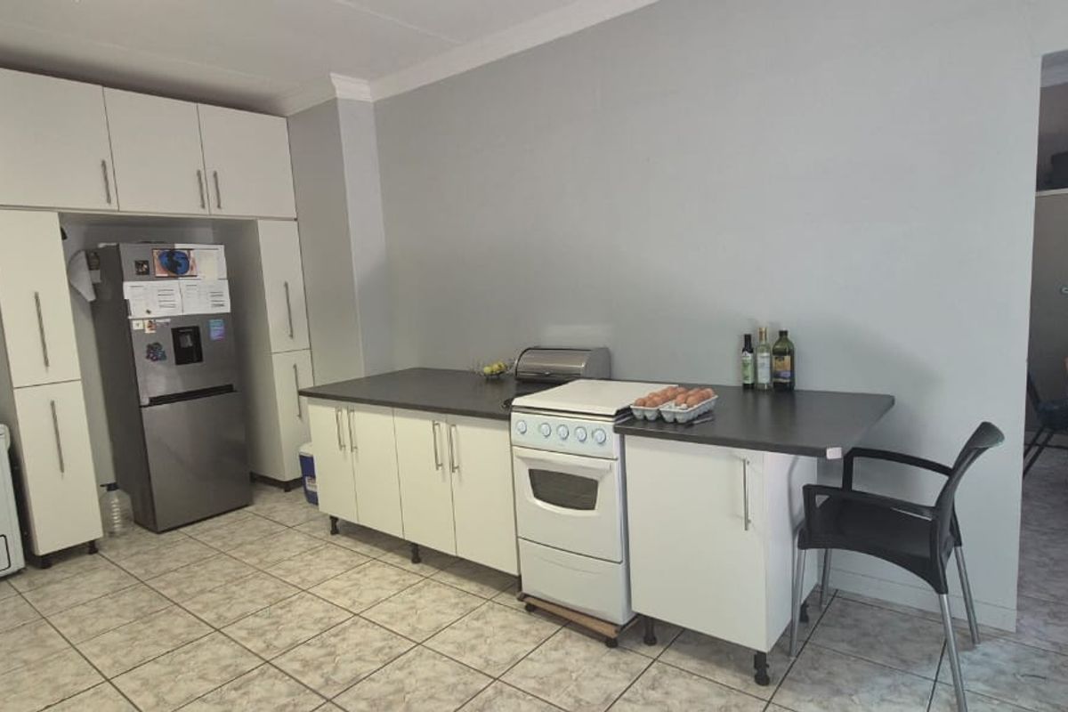 A functional kitchen featuring white cabinetry, tiled flooring, and a freestanding stove, offering a practical layout for daily meal preparation.