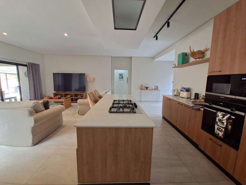 Modern open-plan living area featuring a contemporary kitchen with a central island, gas hob, integrated appliances, and seamless flow to the lounge space.