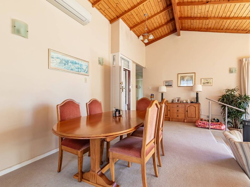 Spacious dining area featuring a high vaulted timber ceiling, neutral wall tones, and carpeted flooring, creating a warm and inviting atmosphere.