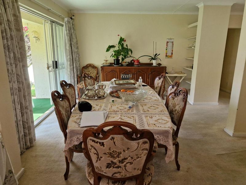 A traditional dining room featuring carpeted flooring, built-in shelving, and a large sliding glass door providing access to the outdoor patio area.