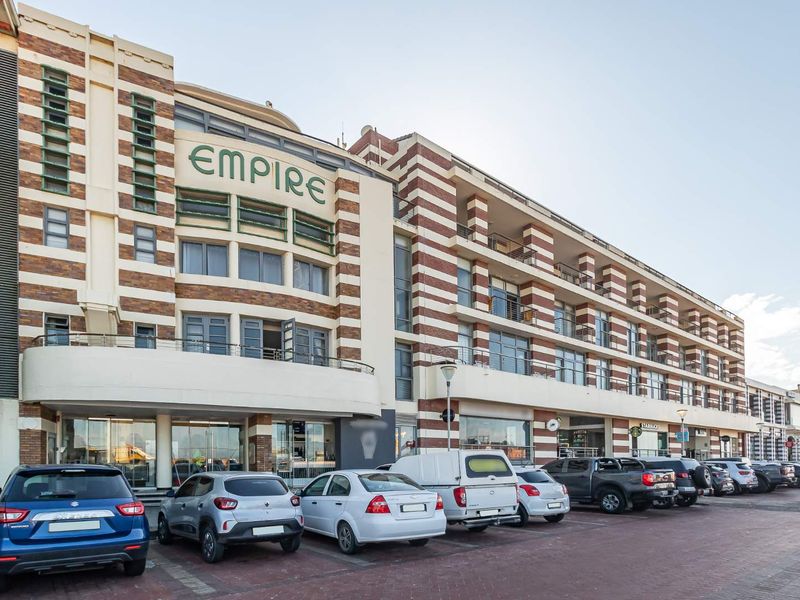 Exterior view of the Empire building featuring a distinctive brick facade, multiple balconies, and a paved parking area at the front entrance.