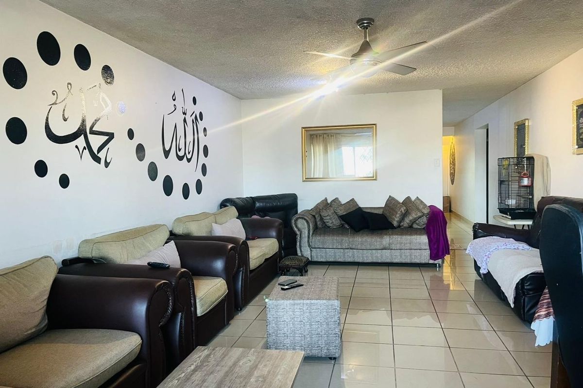 Spacious living room featuring ceramic floor tiles and a ceiling fan, offering a functional layout for comfortable family living.