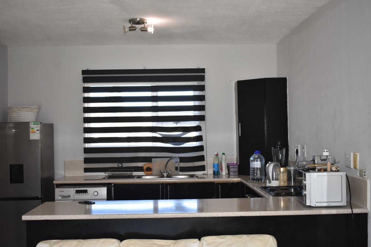 A functional kitchen featuring dark cabinetry, a breakfast bar, integrated sink, and built-in hob, offering a practical layout for daily meal preparation.