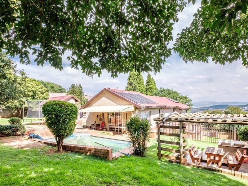 Rear view of the property featuring a swimming pool, paved patio with a pergola, and solar panels installed on the roof.