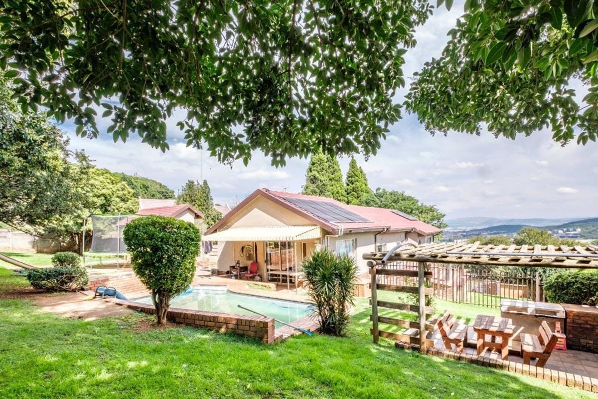 Rear view of the property featuring a swimming pool, paved patio with a pergola, and solar panels installed on the roof.