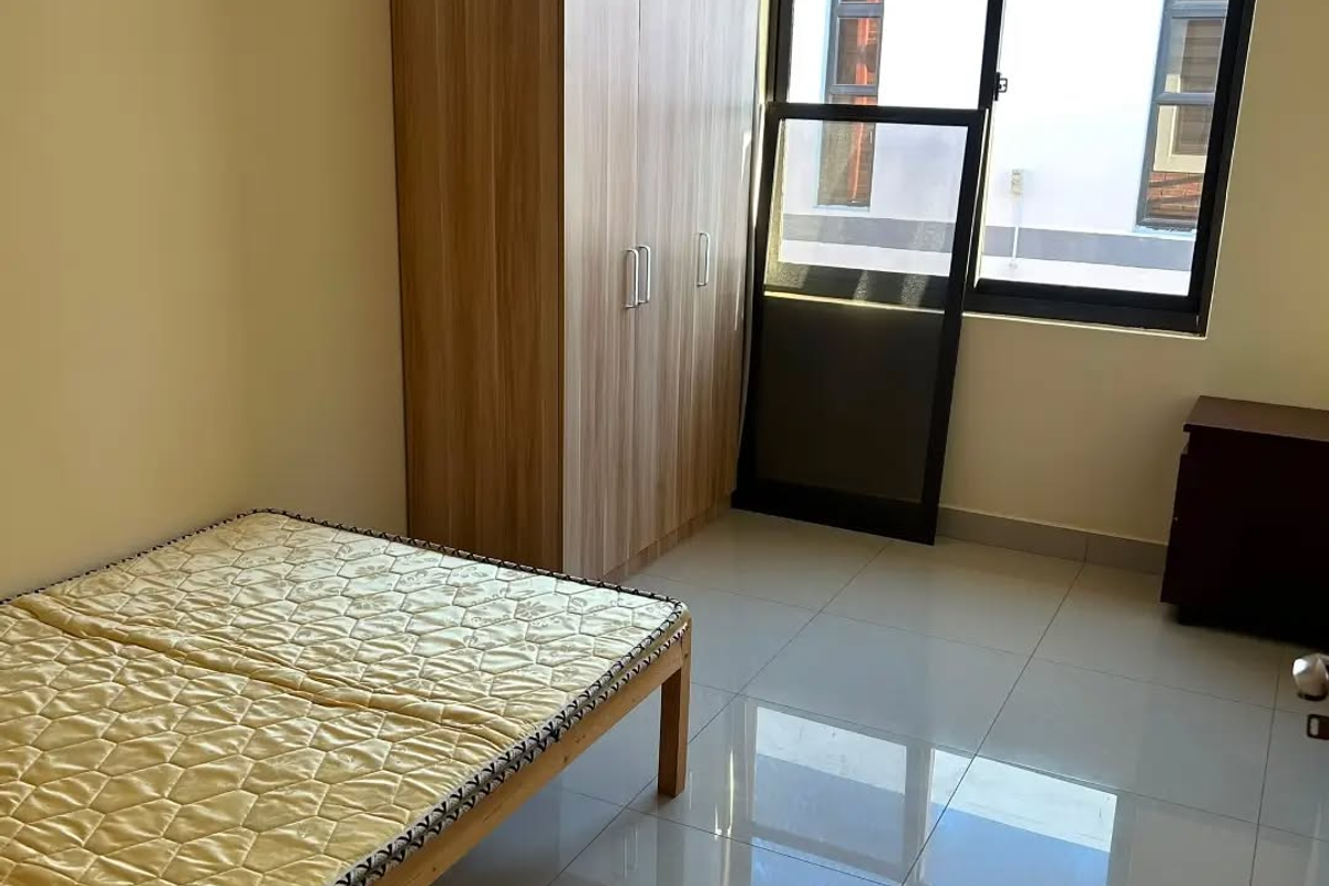 A bright bedroom featuring polished tiled flooring, neutral walls, and a large sliding window providing natural light.