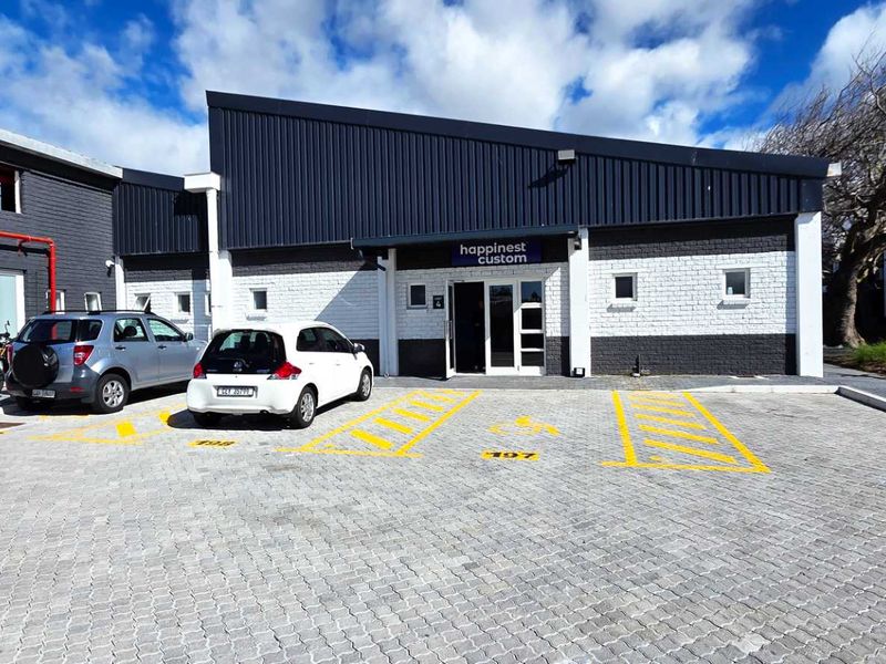 Front exterior view of an industrial unit featuring a paved parking area, painted brick facade, and modern metal roofing.