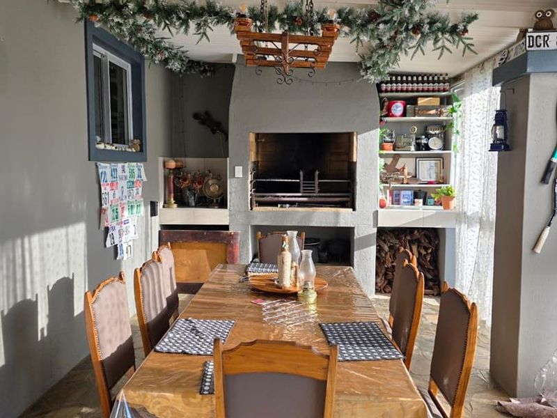 Covered patio area featuring a built-in braai, stone flooring, and integrated shelving, ideal for outdoor dining and entertainment.