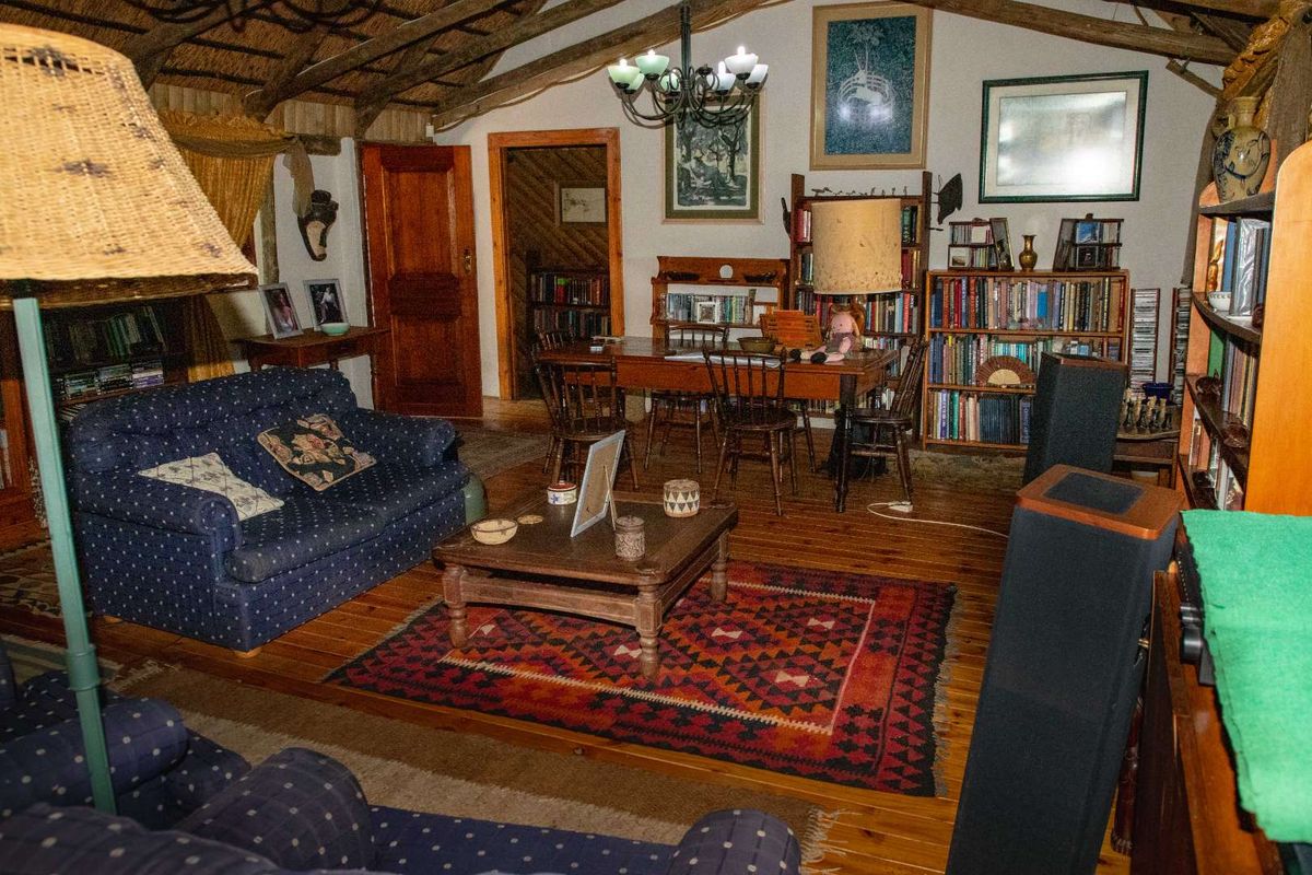 A spacious living area featuring exposed timber roof trusses, a thatched ceiling, and warm wooden flooring, creating a rustic and cozy atmosphere.