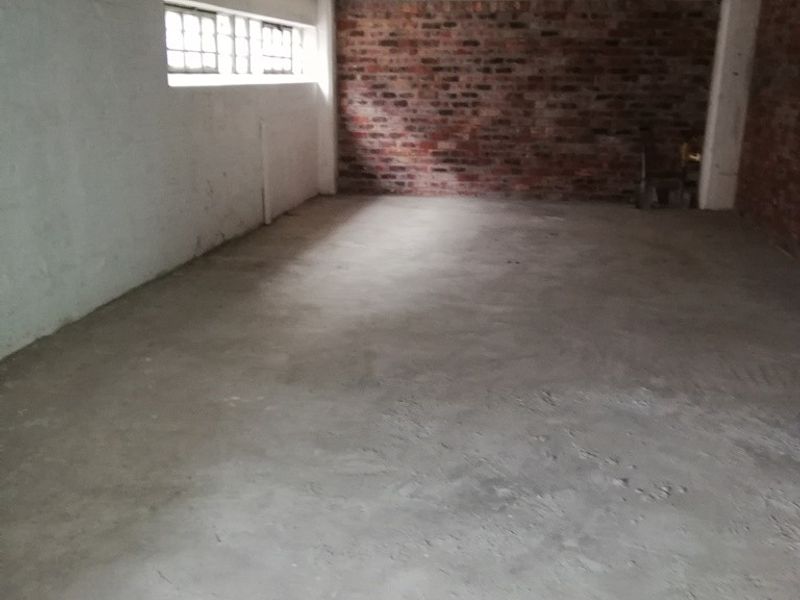 An unfinished utility space featuring exposed brick walls, a concrete floor, and high-level windows, offering a blank canvas for renovation or storage use.